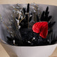 A black preserved floral arrangement with a red anthurium flower