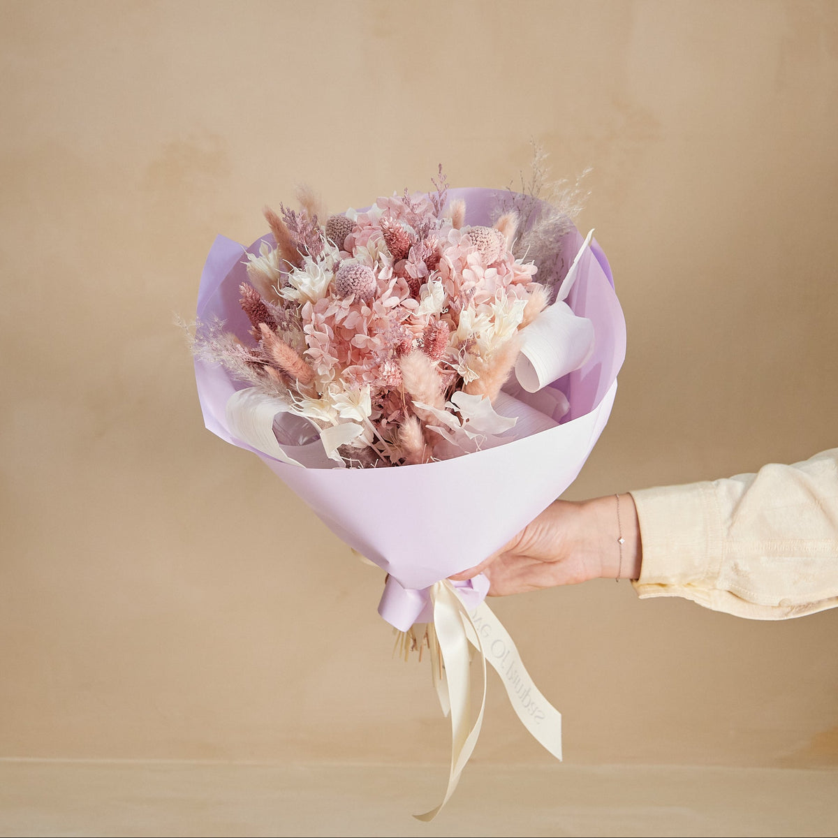 Preserved and dried flower bouquet in pink and lilac colors including preserved hydragea